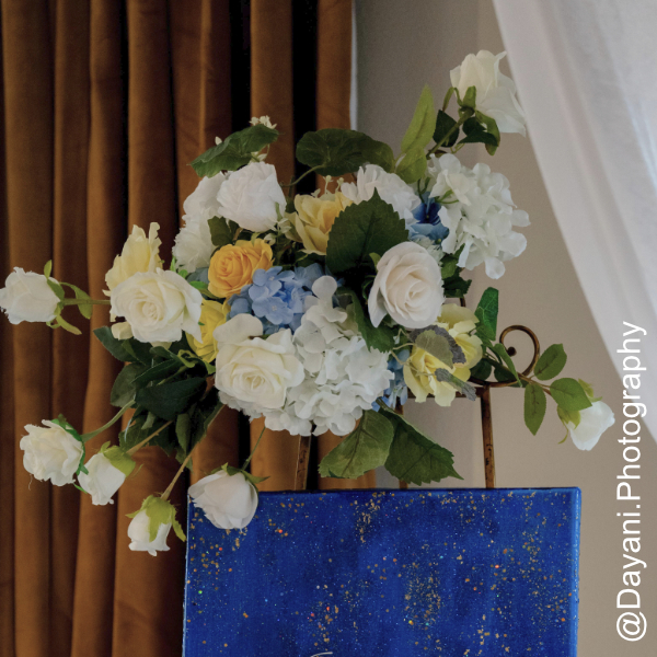 white blue yellow floral centerpieces above gold easel