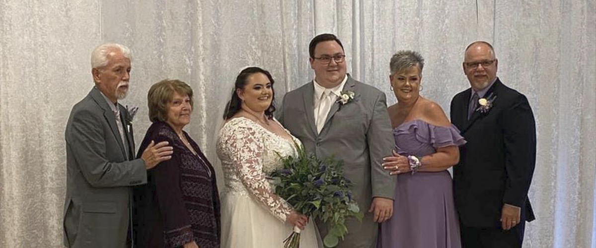 photo of bride and groom with bridal party in front of white curtains